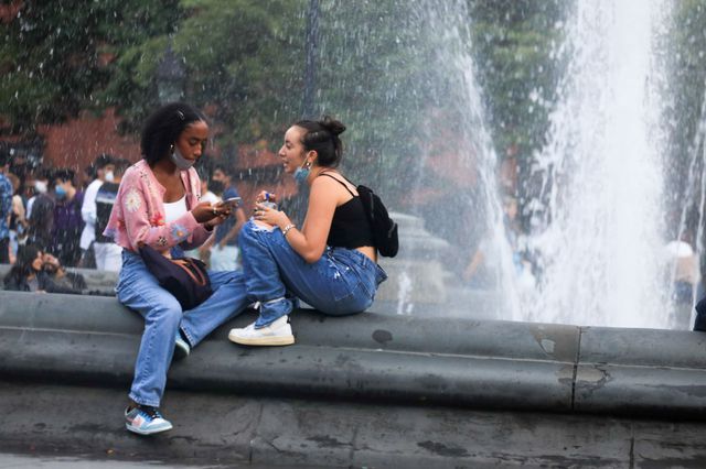 Two people sit and talk at the edge of the fountain in Washington Square Park on September 1, 2020.